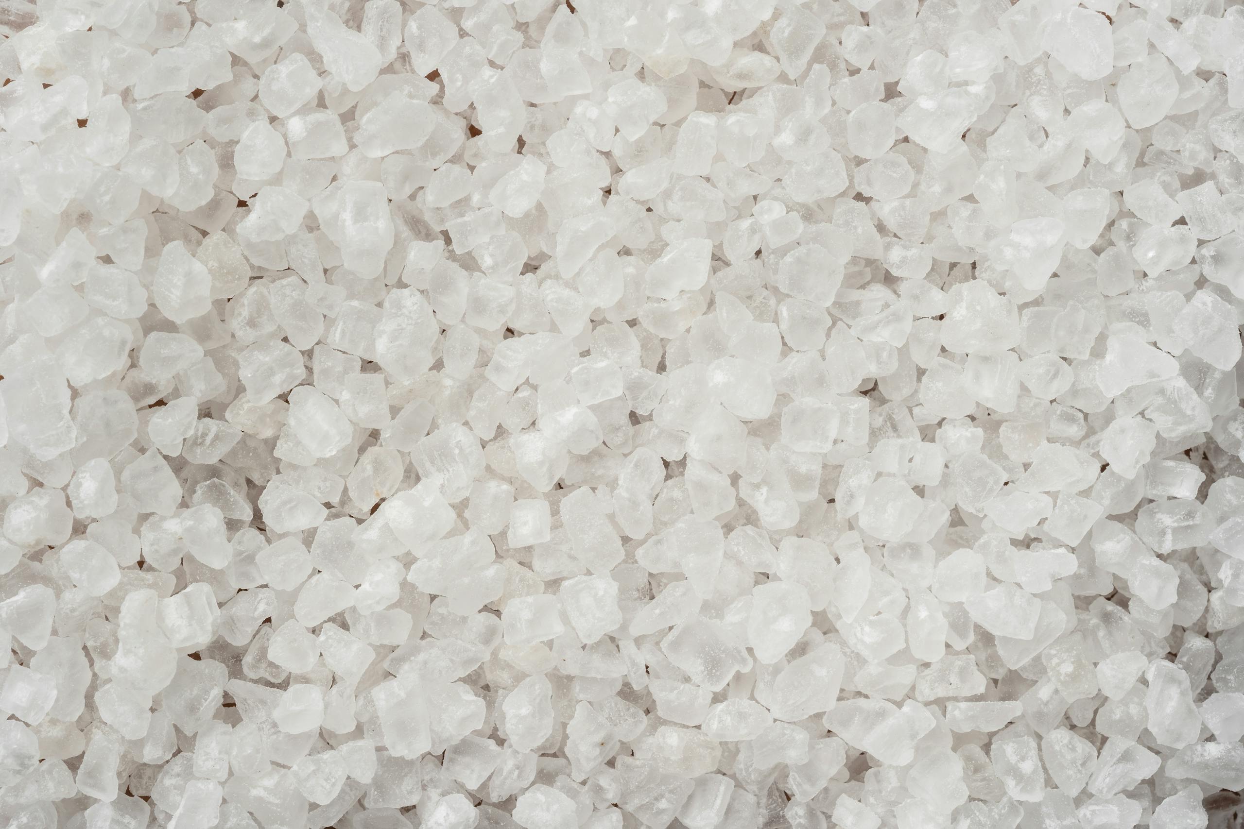 Detailed image showing coarse white sea salt crystals with a textured surface.