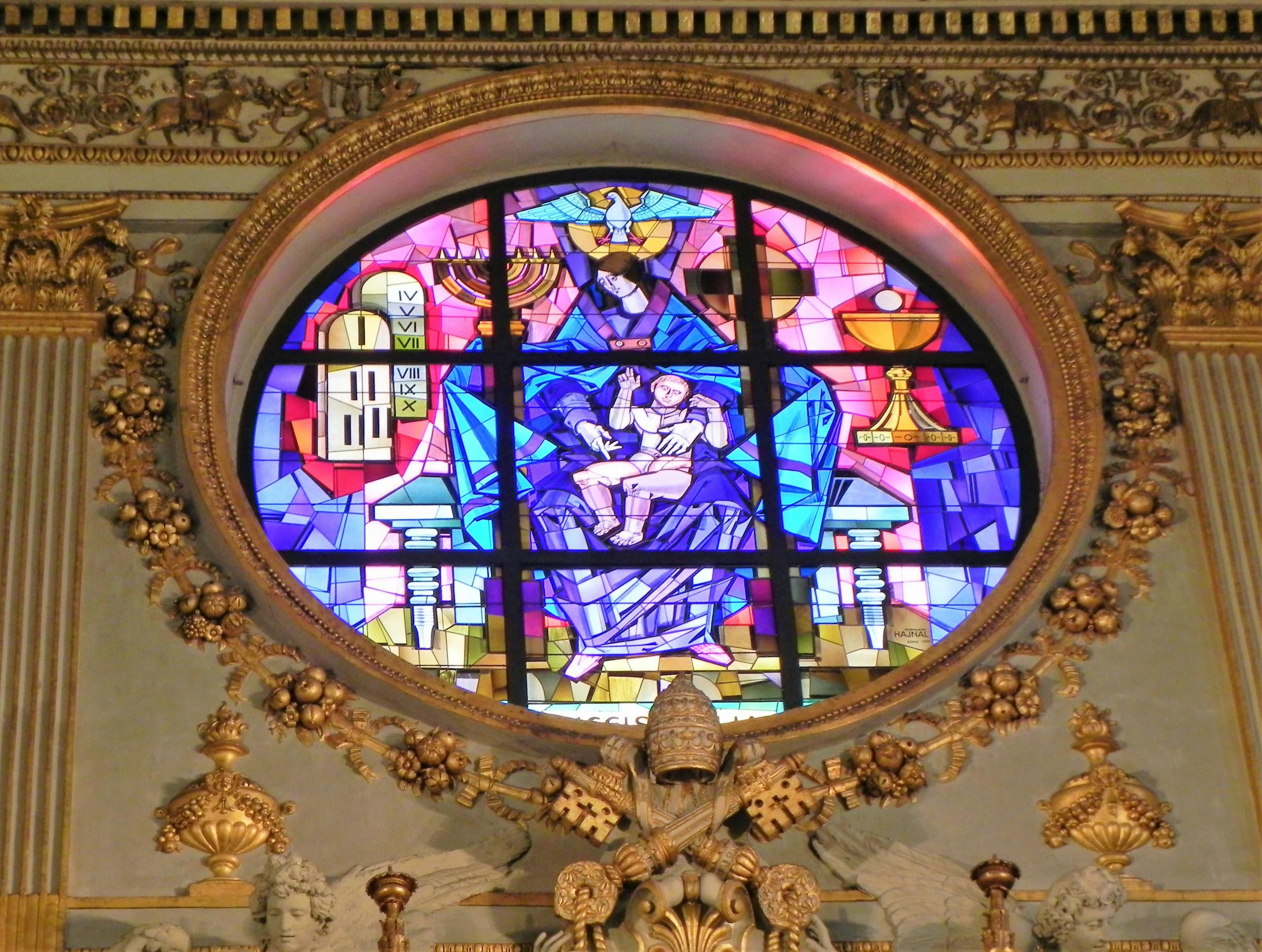 Ornate stained glass window inside a historic church in Rome, Italy, showcasing religious art.